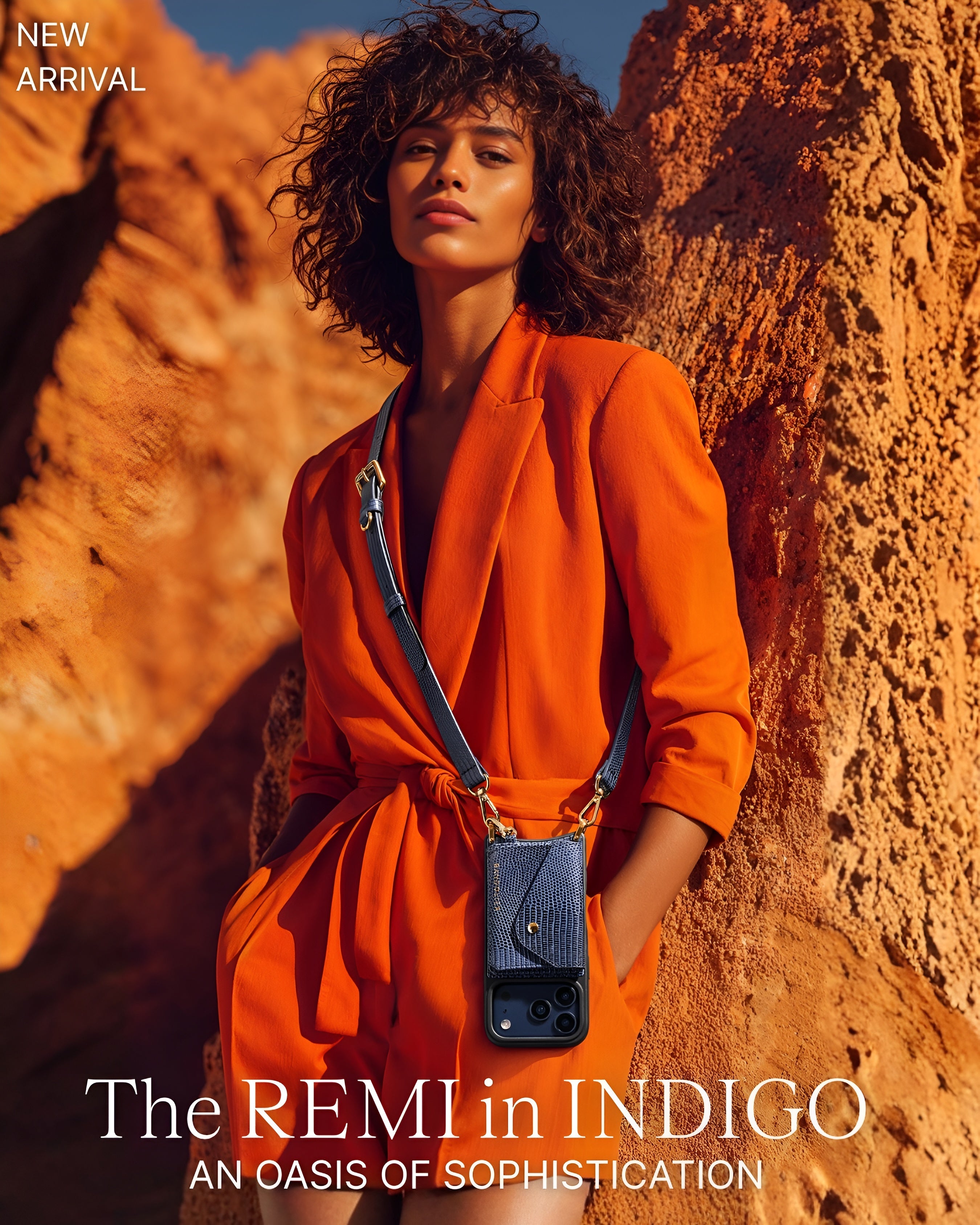 Woman wears an orange outfit with an indigo Bandolier crossbody phone case featuring gold accents.